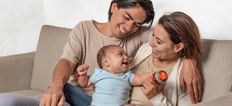 mother and father with infant child on a couch