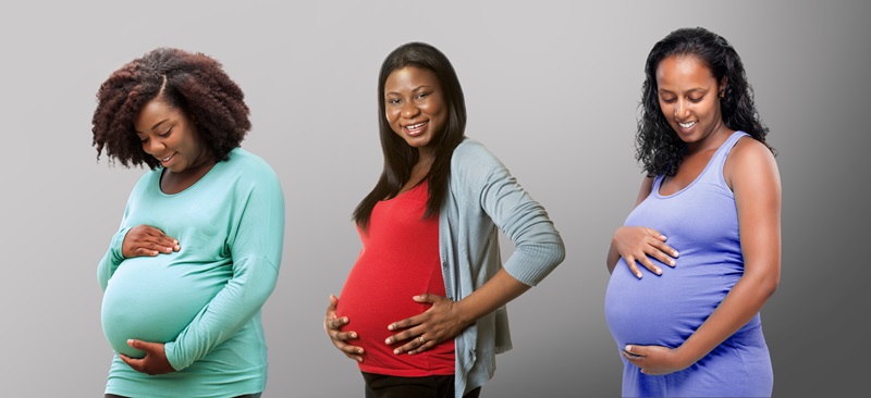 three pregnant women holding their stomachs