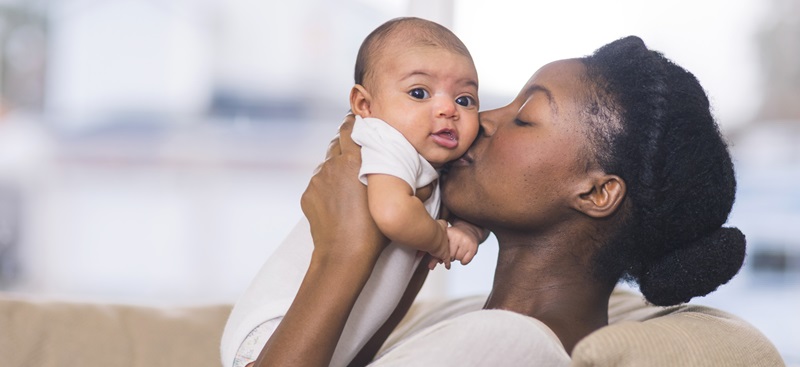 mother kissing infant child on the cheek